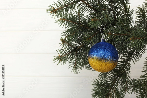 Fototapeta Yellow-blue New Year's ball as the colors of the Ukrainian flag. Closeup of Christmas Yellow-blue ball on Christmas Tree beautiful background for design and decoration, new year concept.