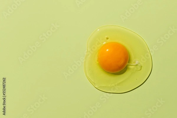 Fototapeta Raw egg yolk on a green background. View from above