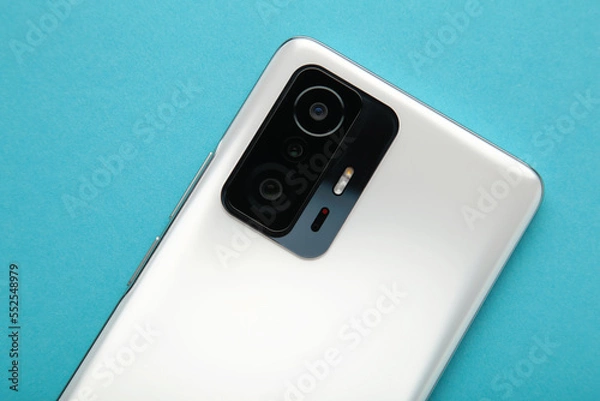 Fototapeta Mobile phone camera, flash lens on blue background.