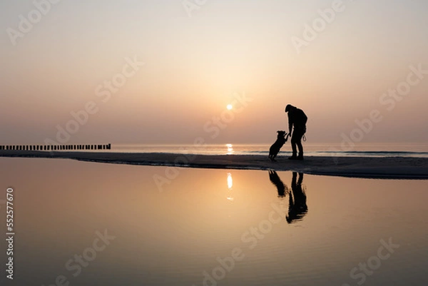 Obraz mann mit Hund vor Sonnenuntergang am Meer, silhouette