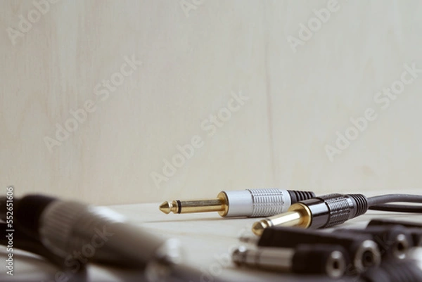 Fototapeta Set of audio jack adapter 6,3 mm and 3,5 mm and various audio jack cables on a wooden bench. Shallow focus. Audio technology and rehearsal room concept.
