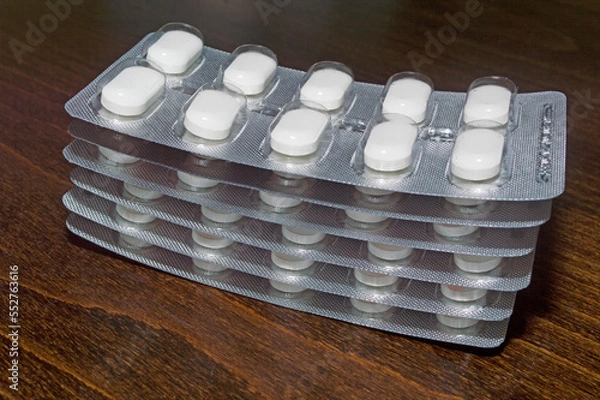 Obraz Blisters of tablets on a wooden surface. A medicinal product.