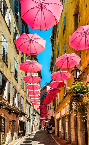 Obraz Historic tenement houses and narrow streets decorated with pink umbrellas of old town quarter of perfumery city of Grasse in south France