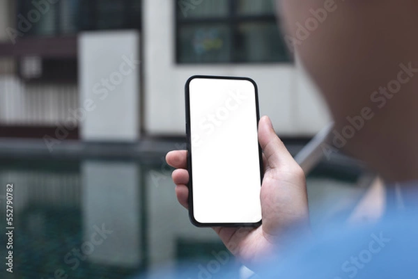 Fototapeta Mockup image of mobile phone for advertising. Mock up image of man hand holding and using smartphone with blank screen for mobile app design or text advertisement