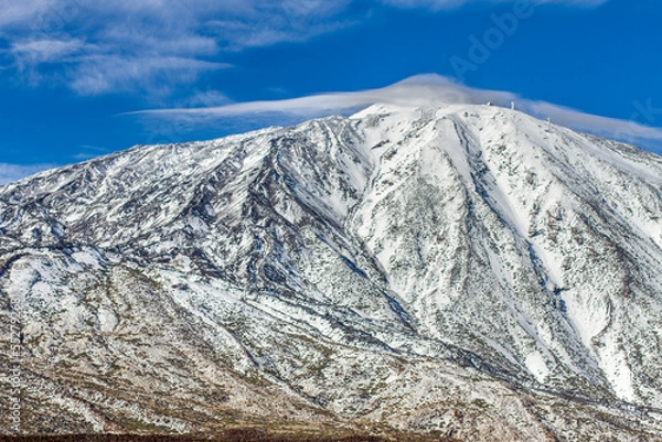 Fototapeta snow-capped volcano of Teide in winter. Snowy mountain with clear blue sky with some frayed clouds. Tenerife, Canary Islands, Spain.