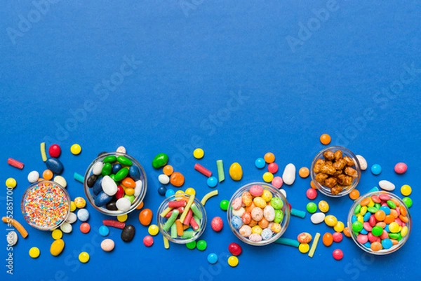Fototapeta different colored round candy in bowl and jars. Top view of large variety sweets and candies with copy space