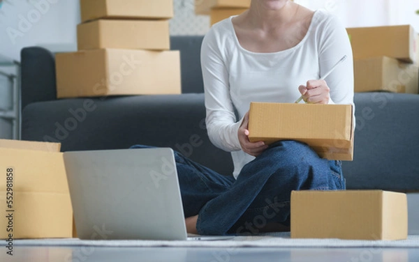 Fototapeta Small business entrepreneur using laptop computer, checking order from customer. Startup small business, Online selling, E-commerce concept.