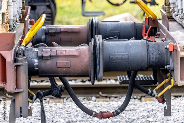 Fototapeta Close up detail of iron connection of two train wagons. Railway car coupler and train buffers. Buffers and chain coupler.