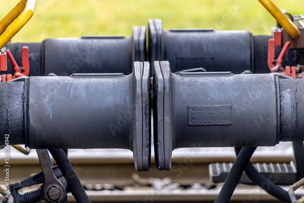 Fototapeta Close up detail of iron connection of two train wagons. Railway car coupler and train buffers. Buffers and chain coupler.