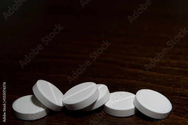 Obraz White round tablets on a wooden surface. A medicinal product.