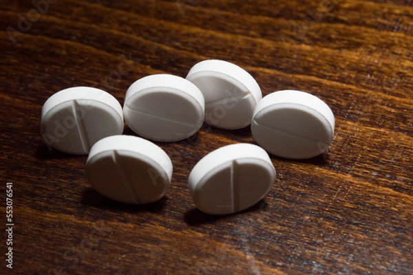 Obraz White round tablets on a wooden surface. A medicinal product.