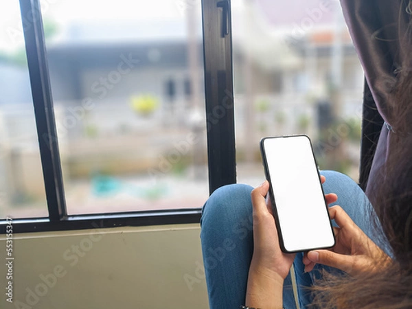 Fototapeta Close-up of a woman hand holding a smartphone white screen is blank .Mockup.