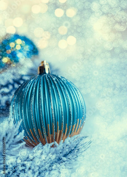Obraz Christmas dark blue balls with sparkles on white snow and snow-covered pine branches. Beautiful blurred background and yellow bokeh. Toned image. Airy atmosphere. Shallow depth of field