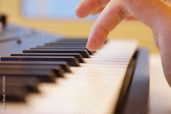 Fototapeta Keyboard keys close up. Right hand is going to play a note. Professional equipment for studio production. Music production and performance concept.
