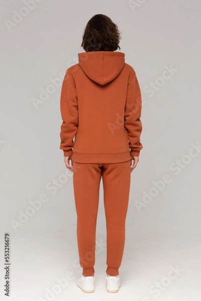Obraz Woman with thick curly hair in a brown suit of hoodies and sweatpants. Shot from the back. Mock-up.