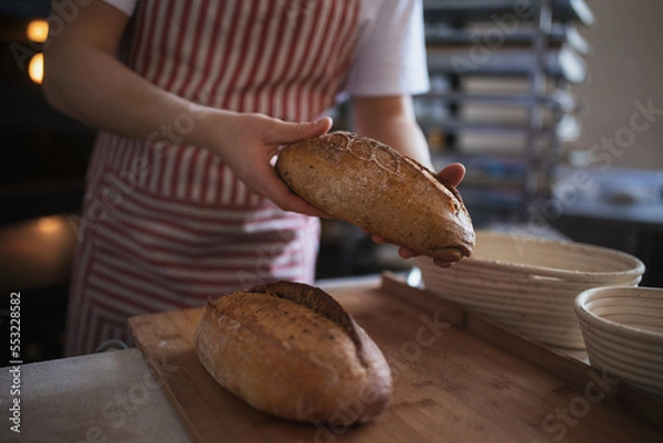Fototapeta Close-up of baker with fresh bread in bakery.