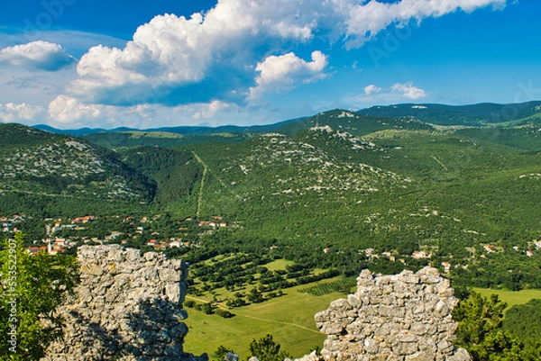 Fototapeta view through a hole in an ancient wall on a mountain