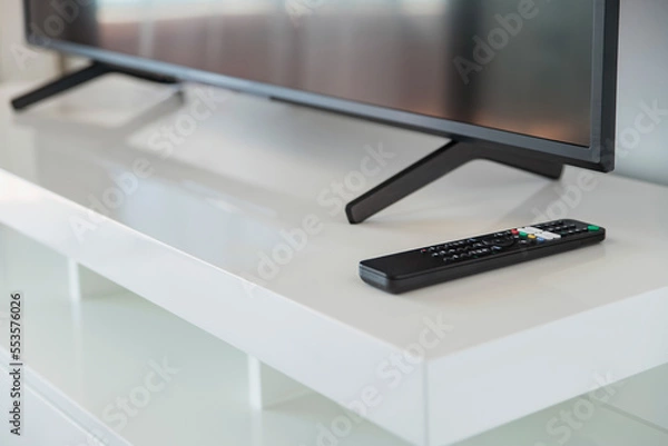 Fototapeta Remote control on the coffee table next to the TV