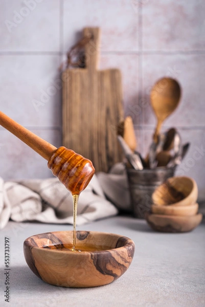 Fototapeta Healthy natural honey in a bowl with a wooden dipper in the kitchen