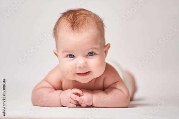 Fototapeta portrait of a smiling baby on a white background looking into the camera