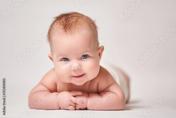 Fototapeta portrait of a smiling baby on a white background looking into the camera