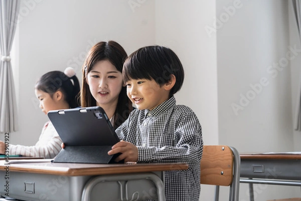 Fototapeta タブレットPCを使った授業をする日本人小学生の男の子と女性教師