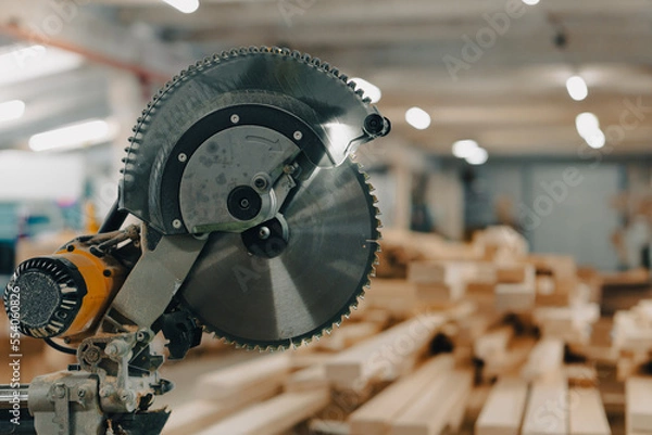 Fototapeta A miter saw in a factory house with a pile of wood chips in the background