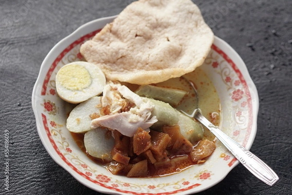 Fototapeta Lontong opor is Indonesian traditional food made from chicken cooked with coconut milk and spices. Served with egg, compressed rice cake, and prawn cracker.