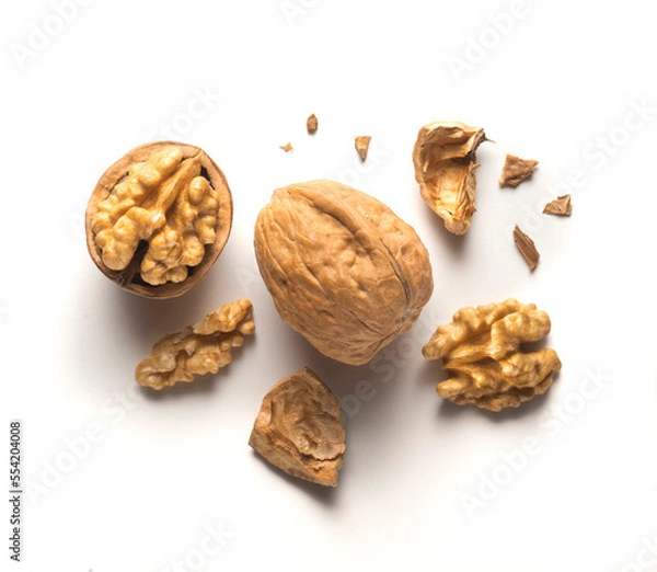 Fototapeta whole walnut plus open walnut with scattered shell parts on white background
