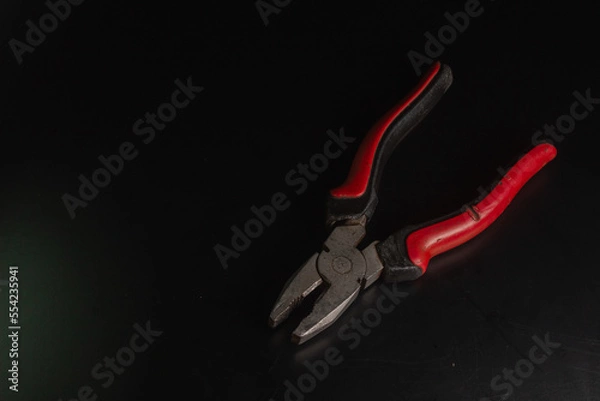 Obraz Pliers Open metal nippers with a red and green handle isolated on black background