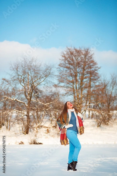 Obraz Vinnytsia, Ukraine. December 23, 2022: A girl stands on a frozen lake in the cold in winter. It's December outside. All around the trees are covered in snow. Beauty in Finland