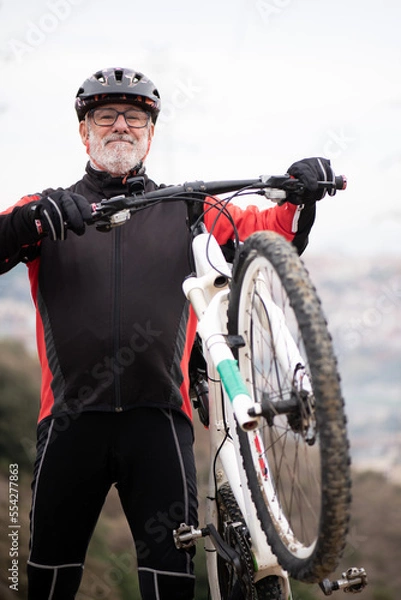 Fototapeta portrait of a retired older man dressed as a bicyclist riding his bike