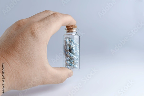 Obraz Glass jar with a tablet in the hand on a blue background