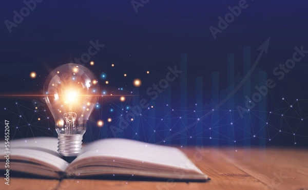 Fototapeta Light bulb on open book with growing graphs of stock market, Educational knowledge and business education concepts, Reading for inspiration and new idea to business grow in the future.