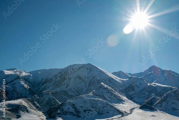 Fototapeta Panoramic view of snowcapped mountains illuminated by the sun. Winter. beautiful clear blue sky in daylight. impressive view of the mountain peaks