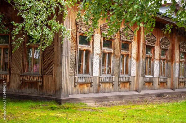 Fototapeta Reiny clouds in the cold autumn sky over  village with small wood log local houses and low fences in the park. Travelling on the suburb roads. People living