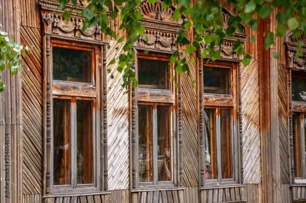 Fototapeta Reiny clouds in the cold autumn sky over  village with small wood log local houses and low fences in the park. Travelling on the suburb roads. People living
