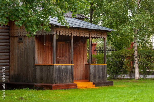 Fototapeta Reiny clouds in the cold autumn sky over  village with small wood log local houses and low fences in the park. Travelling on the suburb roads. People living