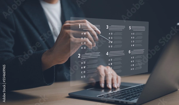 Fototapeta Businessman with evaluating questionnaire on online laptop computer. assessment survey online, choose correct answer in test, questions test, online exam, quiz knowledge, filling out an survey form.