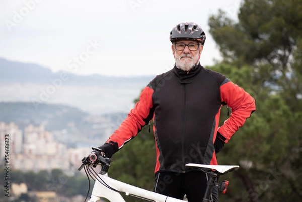 Fototapeta portrait of an older man dressed as a black and red cyclist with his bicycle