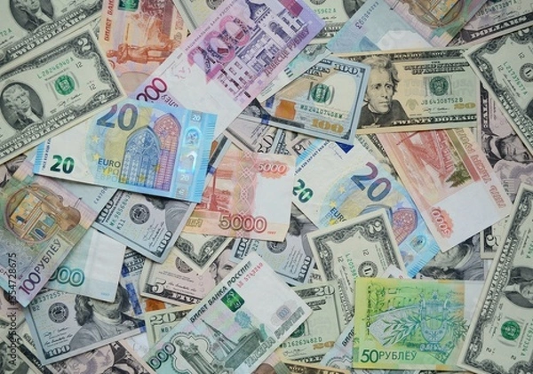 Fototapeta Flat lay.  On the table, there are money from different countries, dollars, euros, Russian rubles, Belarusian rubles.  A lot of banknotes lie nearby.  Top view, close-up.
