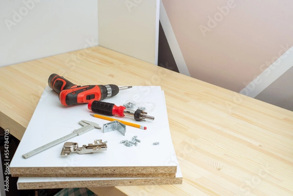 Fototapeta furniture assembly - worker installing cabinet shelf