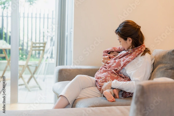 Fototapeta ソファーで赤ちゃんに授乳をするお母さん