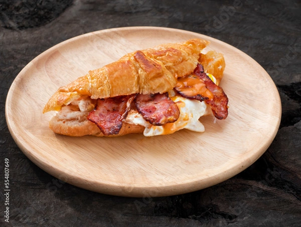 Obraz Croissant sandwich breakfast with egg and crispy bacon on plate.