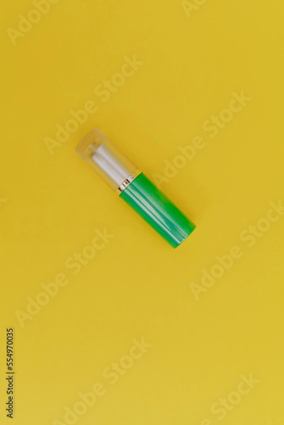 Fototapeta Lipstick with a bright green cap on a yellow background