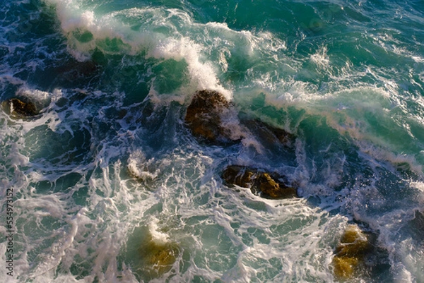 Obraz Sea water breaking on rocks, outdoors, waves and stones, splash and foam, top view.