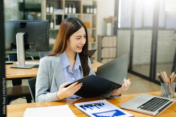 Obraz Asian businesswoman working in the office with working notepad, tablet and laptop documents .