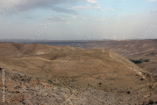 Fototapeta Desert landscape view of sunny rocky cliff with wind turbines in view taken from Shobak Castle, Jordan