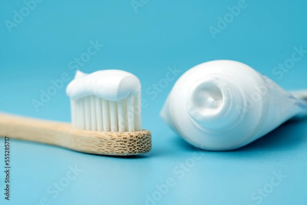 Fototapeta New toothbrush with toothpaste closeup on blue background closeup