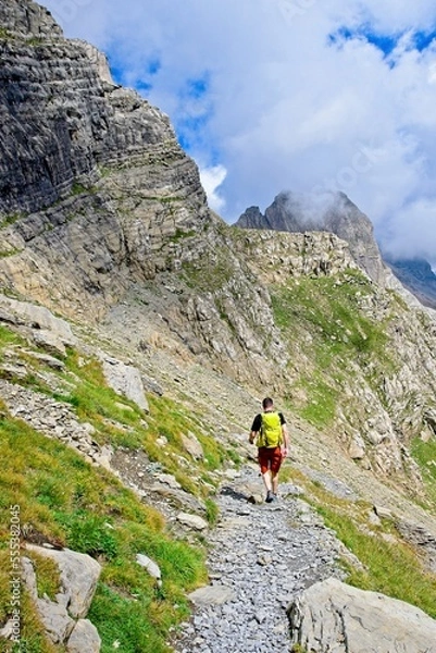 Fototapeta A man hikes the trail to Balcon de Pineta, a popular route in the Spanish Pyrenees
